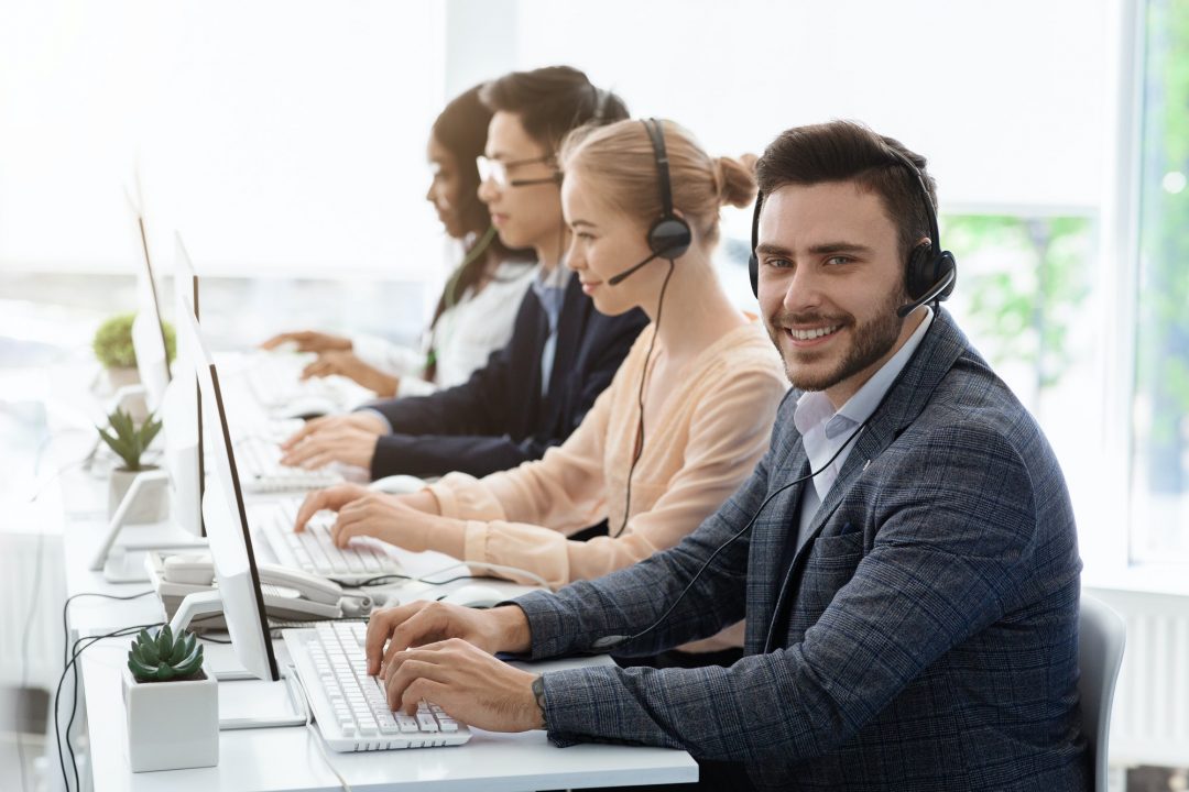 team of customer service agents with headsets working at computers in office empty space - Virtual Assistant Agency